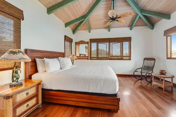 Rest under beautiful rustic architecture! This bedroom features spectacular high exposed-beam ceilings, a comfortable bed, and a cozy reading corner! 🛌🪵✨