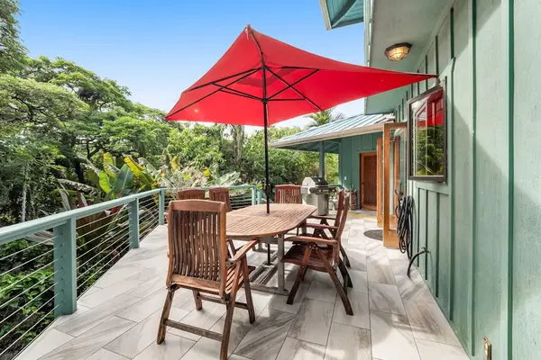 Elevated second-floor deck featuring a wooden dining set, bold red umbrella, and scenic forest canopy views. 🌿☀️