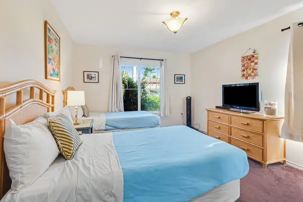 Guest room with two single beds and a flat screen tv.
