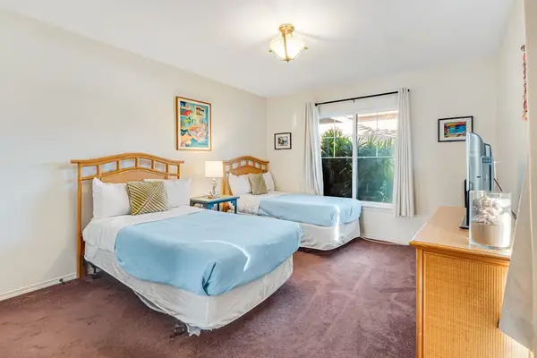 Guest room with two single beds and a flat screen tv.