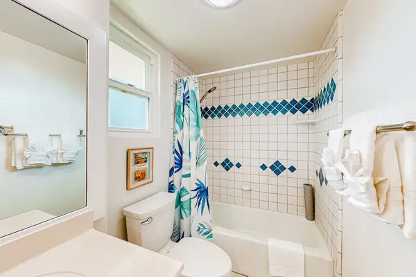 This bright, coastal-themed bathroom features a patterned blue and white tile accent wall above a white bathtub.