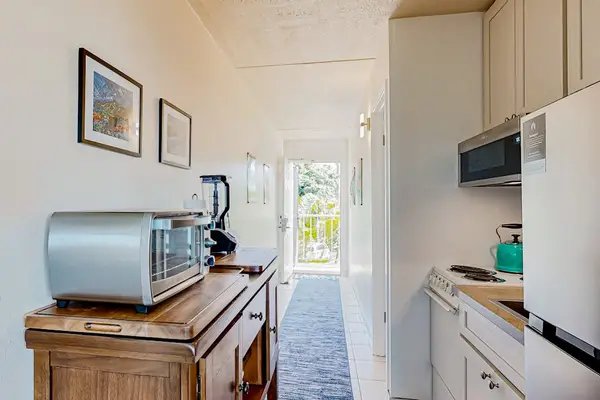 Kitchen area with a Whirlpool over-the-range microwave and a light blue kettle, toaster oven, and Ninja Professional Blender