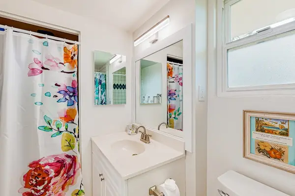 This bright, coastal-themed bathroom features a patterned blue and white tile accent wall above a white bathtub.