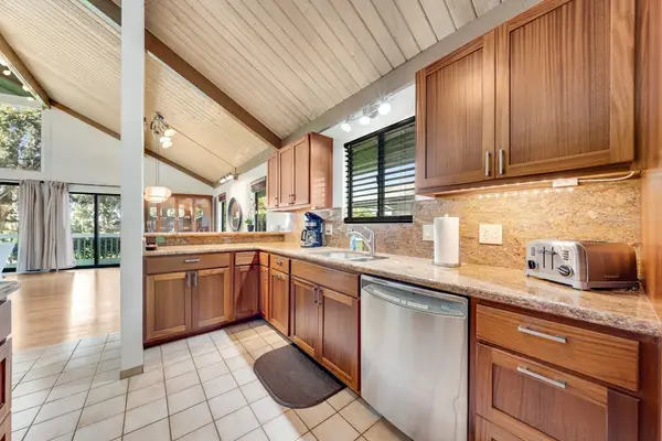 Vaulted kitchen gleams with wooden cabinets dishwasher and generous counters