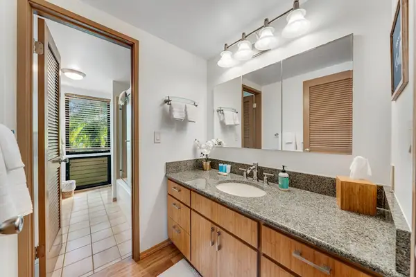 Wide mirror and granite counter brighten the airy tiled bathroom