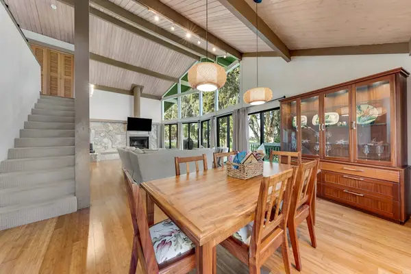 Wooden dining table anchors bright meals beside airy island kitchen
