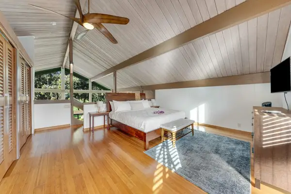 Warm timber floors frame restful bed beside breezy sliding doors