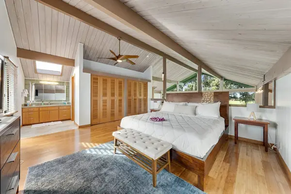 Bright bedroom seating pairs cozy bed views and overhead beams