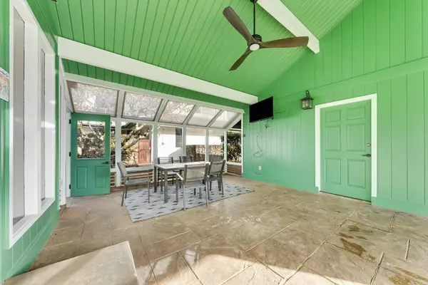 Covered lanai beside cheerful green home and palms