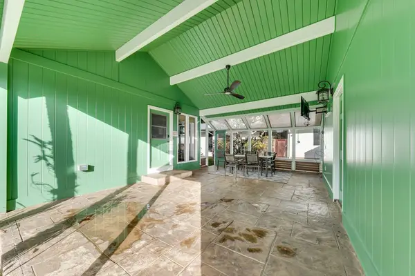 Covered lanai offers sheltered space beside bright green home