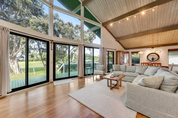 Sun drenched lounge opens toward lawns through dramatic glass walls