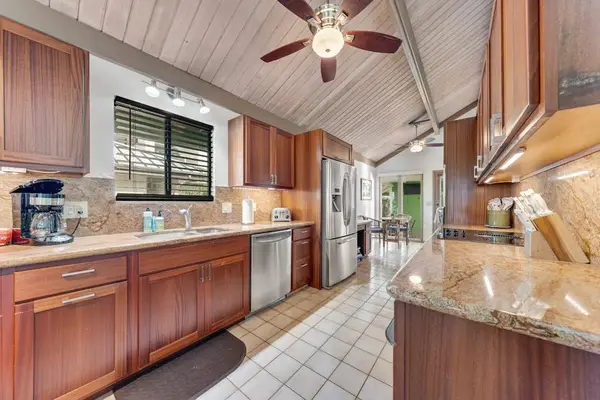 Galley kitchen pairs warm wood cabinetry sparkling counters and daylight