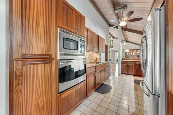 Stainless appliances complement timber cabinets beneath vaulted ceiling and skylight