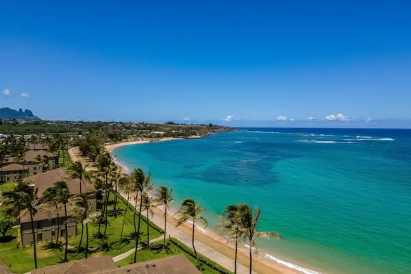 Turquoise water of the Pacific Ocean crashing on to the white sandy beaches while the palm trees sway in the breeze.