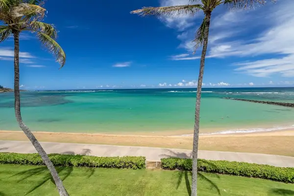 Turquoise water of the Pacific Ocean crashing on to the white sandy beaches while the palm trees sway in the breeze.