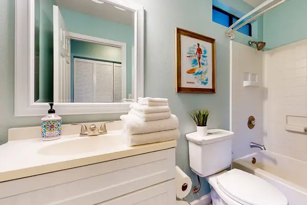 Clean full bathroom featuring a white vanity sink setup, fresh towels, coastal wall art, and a pristine shower/tub combo! 🚿✨