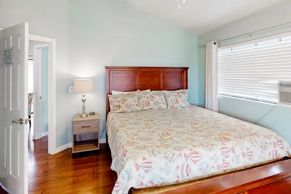 Charming queen bedroom featuring a classic wooden bed setup, matching nightstand, and bright window with privacy blinds! 🛌✨