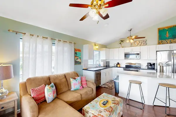 Bright open-concept living room and kitchen layout featuring a cozy sectional sofa, breakfast bar seating, and full appliances! 🛋️✨