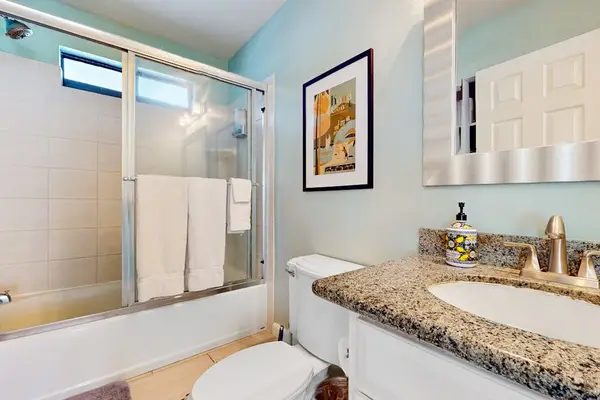 Beautiful full bathroom featuring a premium granite vanity countertop, elegant framed art, and a glass-enclosed shower/tub! 🚿✨