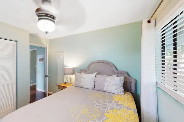Bright queen's bedroom featuring a comfortable bed with an arched headboard, ceiling fan, and a large window! 🛌☀️