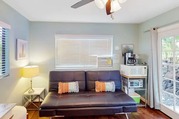 Cozy secondary living room equipped with a convertible sofa, cooling ceiling fan, and a convenient coffee and microwave station! 🛋️✨
