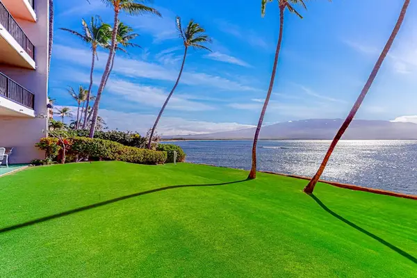 Oceanfront manicured lawns, swaying palm trees, and turquoise Pacific waters create a picture-perfect setting as waves gently crash along the shoreline.