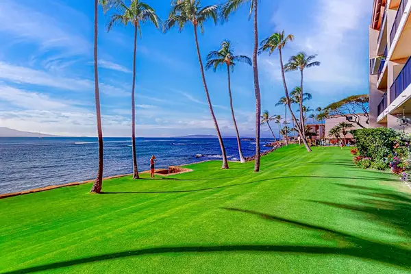 Oceanfront manicured lawns, swaying palm trees, and turquoise Pacific waters create a picture-perfect setting as waves gently crash along the shoreline.