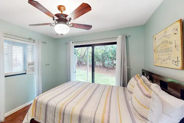 Cozy bedroom featuring a comfortable bed setup, ceiling fan, and sliding doors opening to scenic outdoor views! 🛌🍃