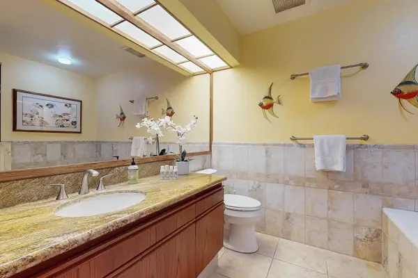 Guest Bathroom Featuring Granite Countertop, Soaking Tub & Coastal Accents