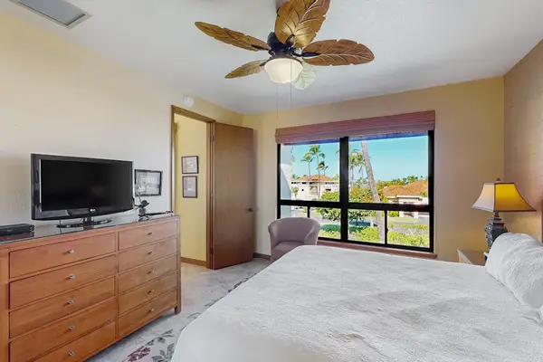 Primary Bedroom View Featuring Flat-Screen TV, Wooden Dresser & En-Suite Access