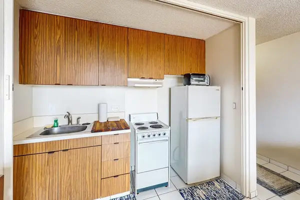 Well-equipped kitchen with wood cabinetry and full-size refrigerator