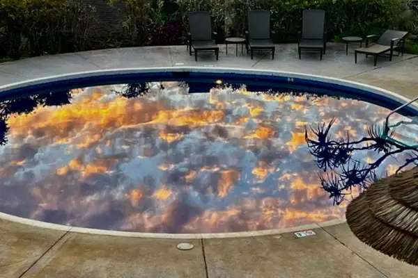 Outdoor hot tub reflects sunset colors beside comfortable poolside seating