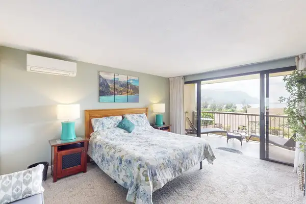 First Bedroom features coastal artwork plush bedding and balcony access