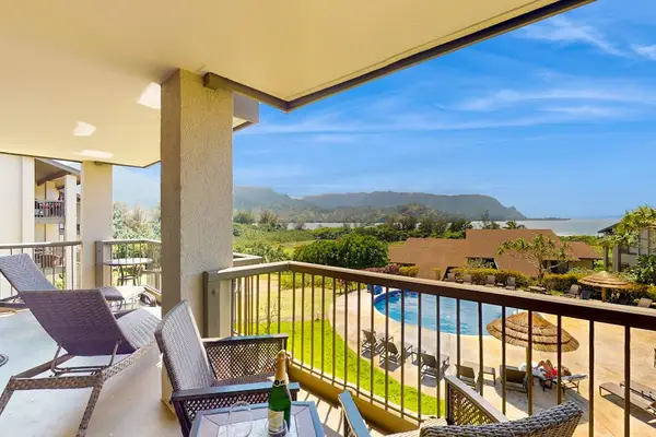 Covered balcony frames emerald mountains beneath sweeping island blue skies