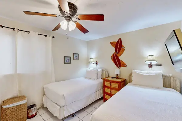 Bedroom with 2 single beds, television, ceiling fan and wall mounted lights.