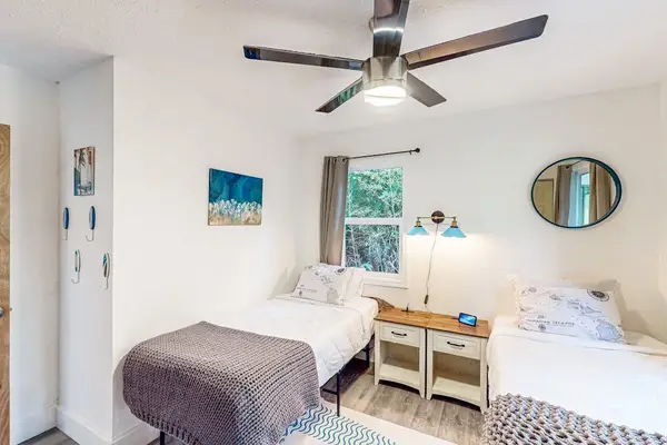 Guest room with two twin beds, ceiling fan and plenty of natural light.