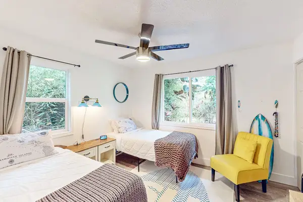 Guest room with two twin beds, ceiling fan and plenty of natural light.