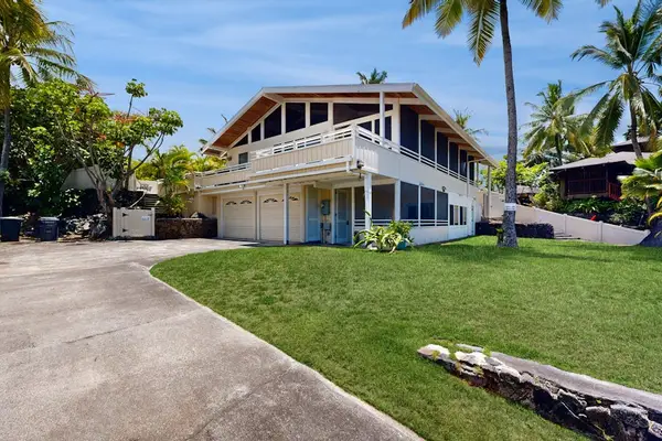 Front lawn and driveway frame the home with tropical landscaping