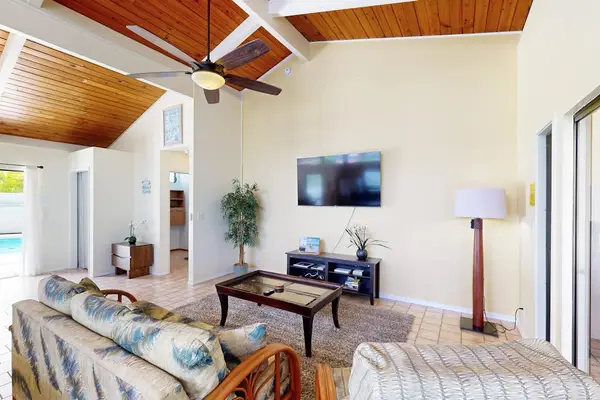 Living room television and sofa face windows beneath wood ceilings