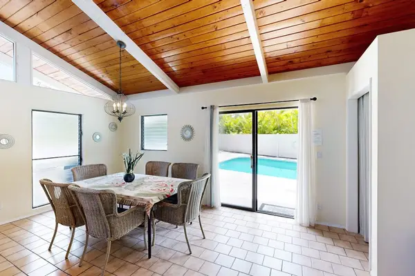 Dining area features glass doors wood ceiling and poolside views