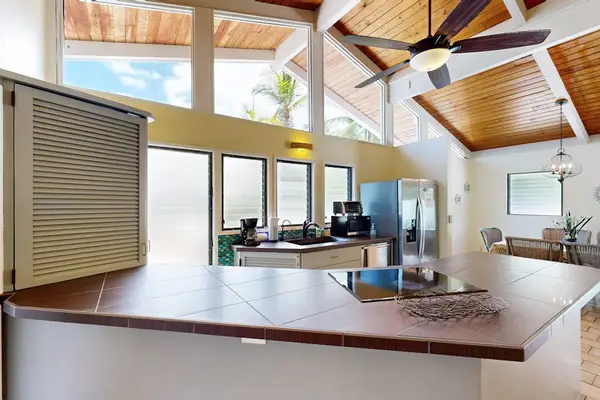 Kitchen counters and appliances sit beneath vaulted wood ceiling beams
