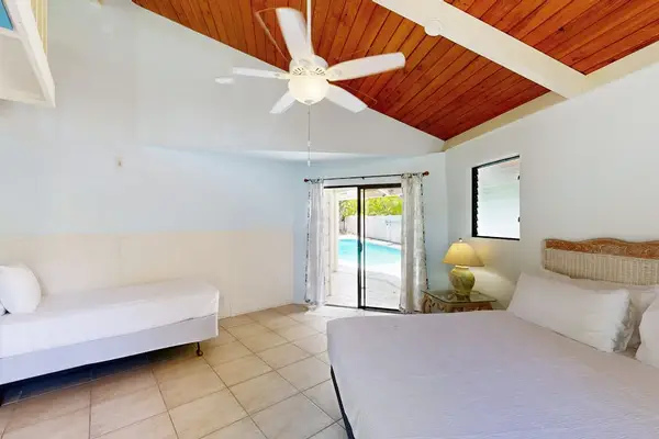 Bedroom sleeping area features ceiling fan windows and tile flooring