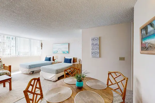 Bright open-concept studio featuring two beds, a dining area, and large windows that fill the space with natural light.