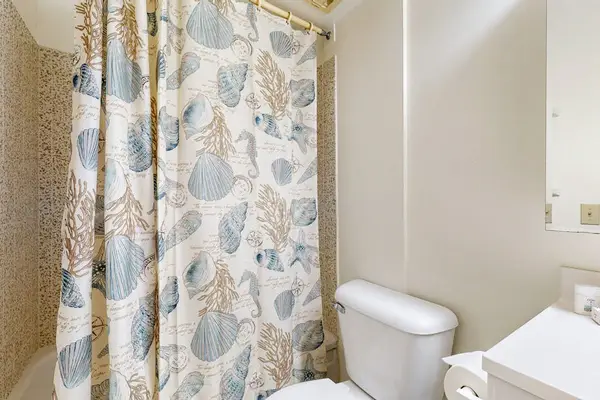 The full bathroom offers a standard shower and tub combination accented by a charming coastal-themed shower curtain.