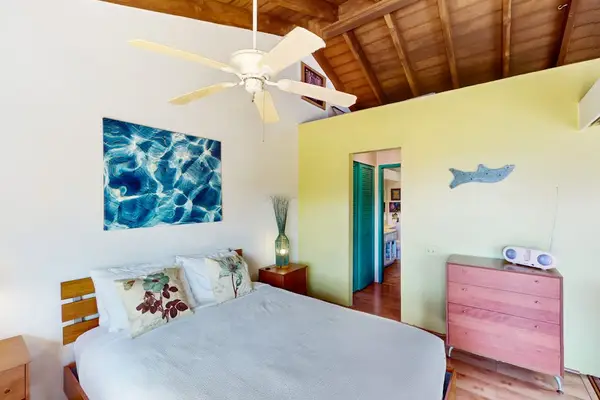 This bedroom features queen bed comfort, ceiling fan, tropical artwork