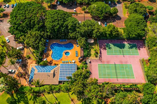 Aerial resort view highlights inviting pool, tennis courts, tropical grounds