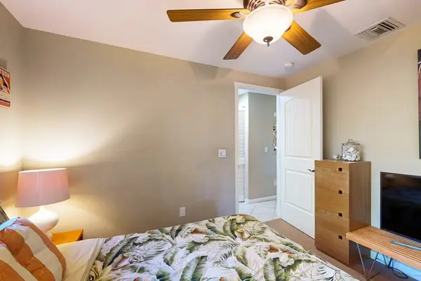 Guest bedroom with queen bed, flat screen tv and a ceiling fan.