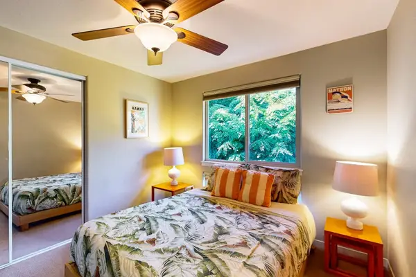 Guest bedroom with queen bed, flat screen tv and a ceiling fan.