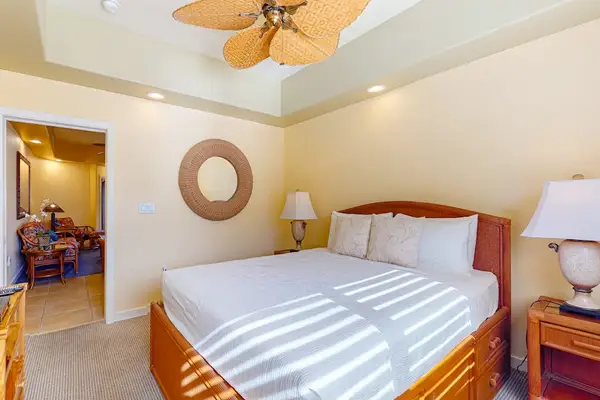 Primary Bedroom Suite Featuring Plush Bedding, Tray Ceiling with Fan, and Decorative Wall Mirror