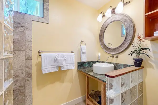 Bathroom Vanity with Vessel Sink, Decorative Round Mirror, and Glass Block Accent Wall
